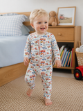 A smiling toddler wearing Little Acres Co 100% GOTS Organic Cotton construction print growsuit