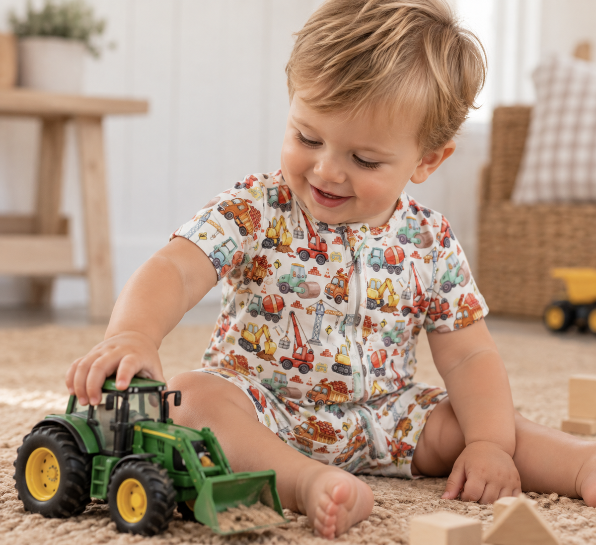 Little boy playing in Little Acres Co construction print organic cotton zip-up romper. Australian brand 