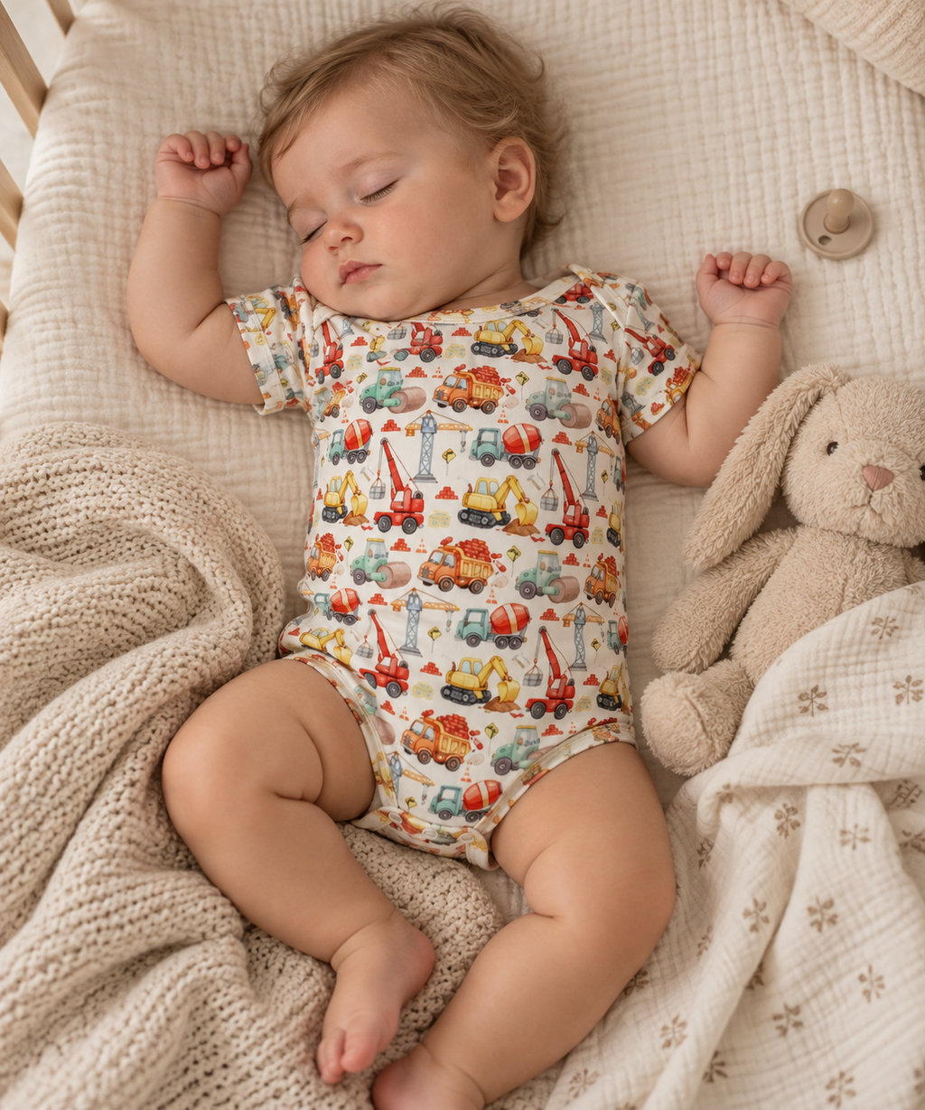 Toddler wearing Little Acres Co construction print organic cotton bodysuit