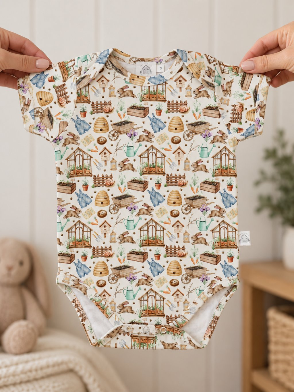 Hands holding Little Acres Co garden print baby bodysuit in GOTS organic cotton