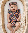 Baby wearing Little Acres Co navy floral organic cotton bodysuit